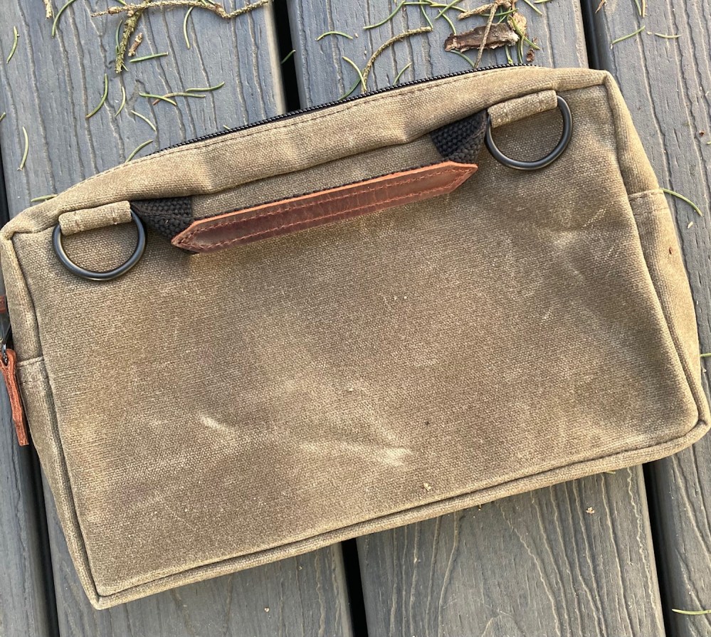 The back of the Man-Bag, Dammit. Two metal rings are attached to each side of the handle strap. Use the rings to clip the provided shoulder strap or clip-on other personal essentials.