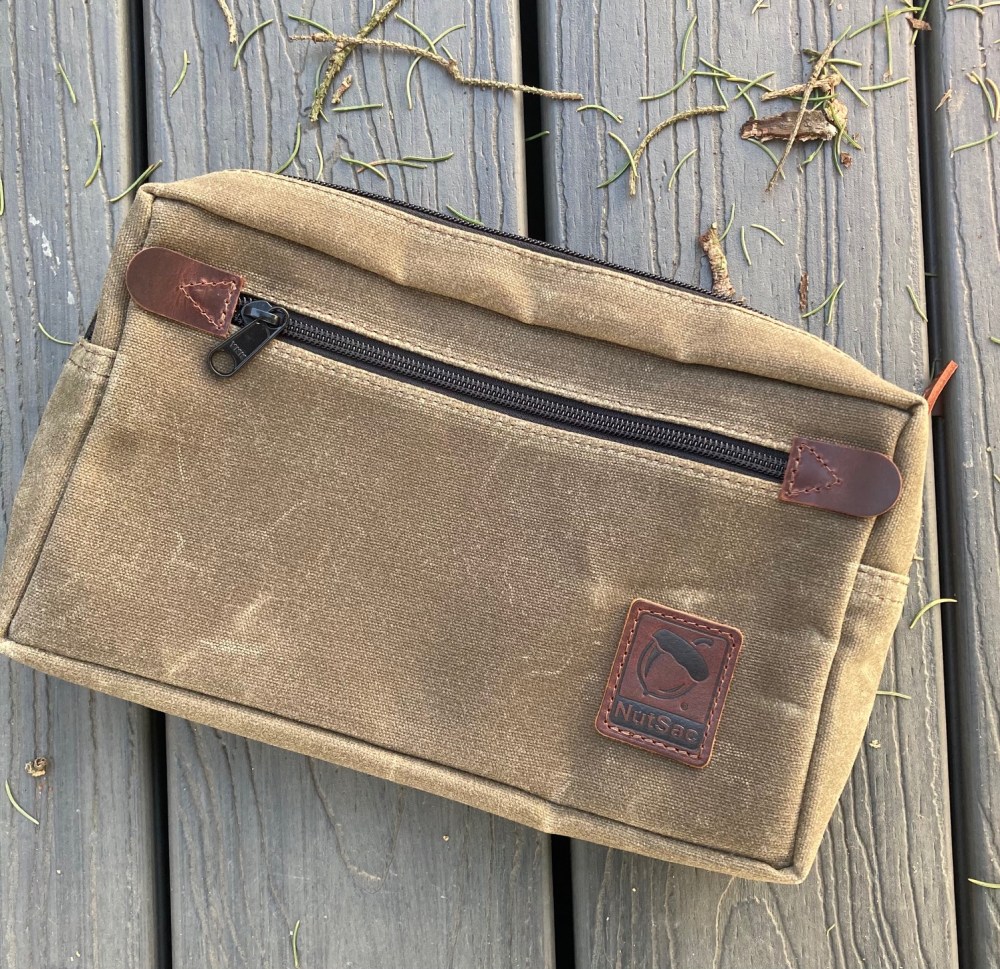 The Man-Bag, Dammit (MBD) from Nutsac in the waxed tan canvas color. Featured on the front is a large zipper pocket.