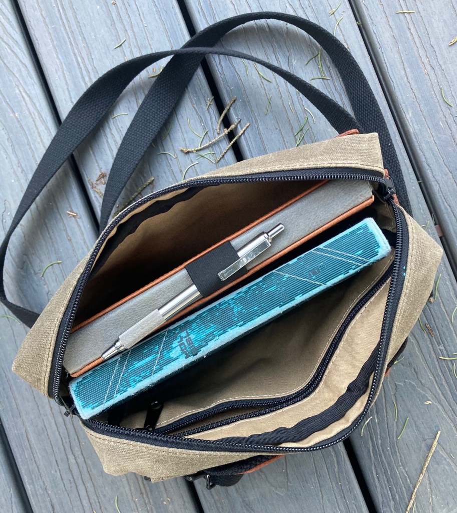 My Lemome grid notebook, Zebra F-701 pen and NIV Thinline Bible inside the Man-Bag, Dammit (MBD). The shoulder straps are clipped to the rings. I do not care for how thin the straps are so I will not use them.